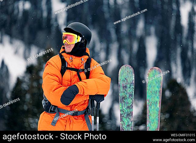 Skier in warm clothing standing with skis and poles