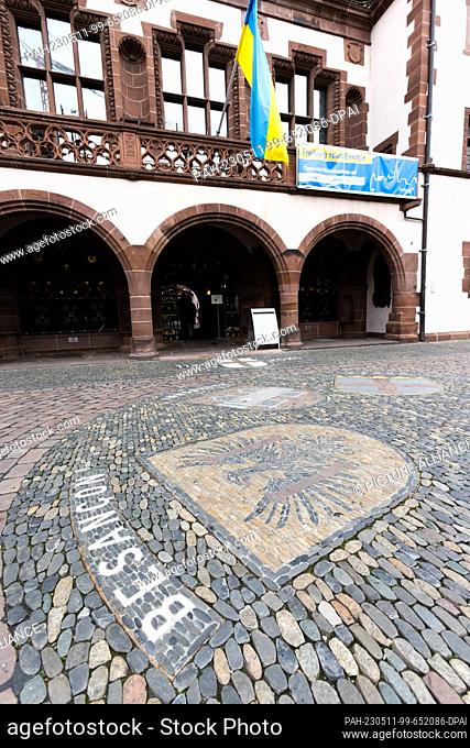 11 May 2023, Baden-Württemberg, Freiburg: The coat of arms of Freiburg's twin city Besançon is embedded in the pavement on the town hall square