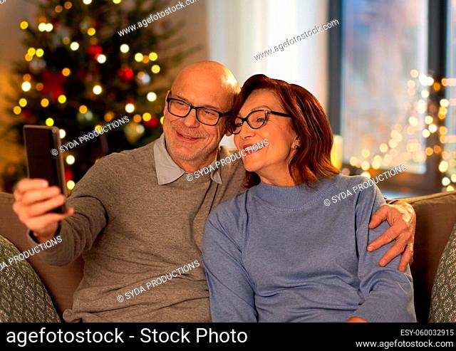 old couple taking selfie with phone on christmas