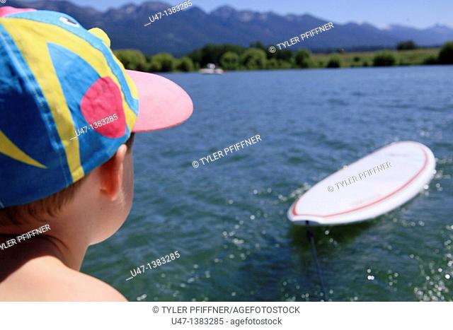 picture of a young boy looking out over the lake and stand up paddle board