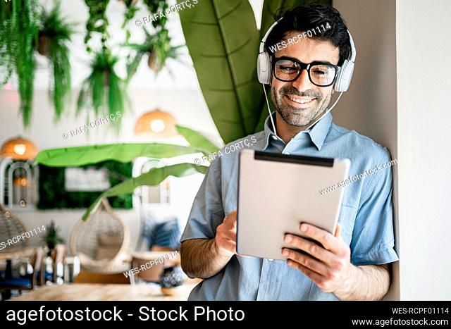 Male freelancer smiling while using digital tablet in cafe