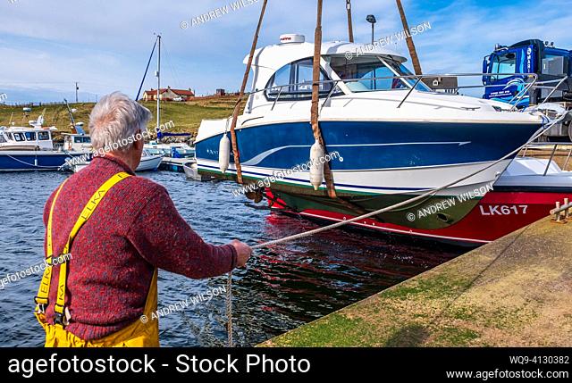 Lifting a small cabin cruiser from the water for repairs in the small harbour at Bridge End, West Burra, Shetland Isles, Scotland