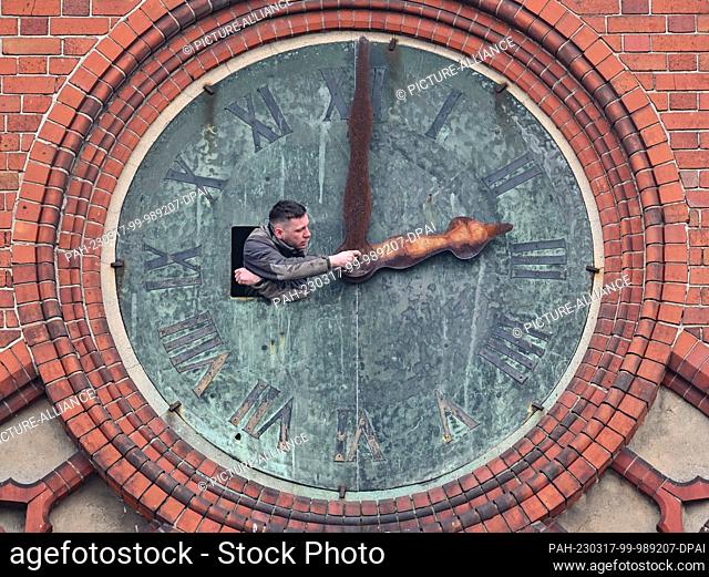 17 March 2023, Brandenburg, Frankfurt (Oder): Michel Lankau, locksmith of the company Bittner Glocken- und Turmuhren, looks out of an opening in the southern...