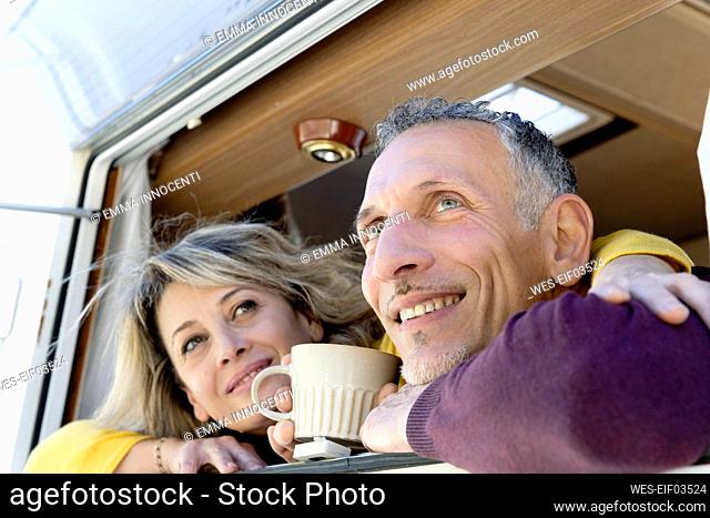 Thoughtful mature couple looking through window of motor home