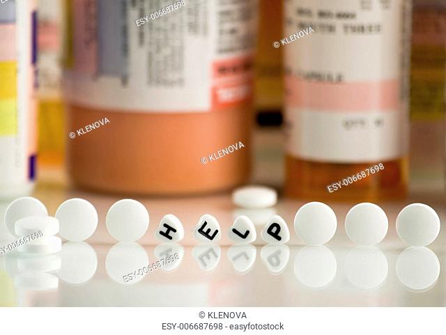 The word HELP spelled with heart-shaped beads and prescriptions. The focus is on a front pill and falls off quickly