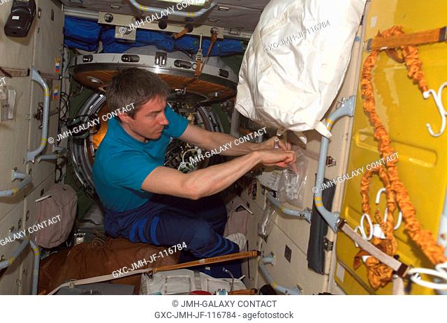 Cosmonaut Sergei K. Krikalev, Expedition 11 commander representing Russia's Federal Space Agency, reaches into a bag for supplies in the Zarya module of the...