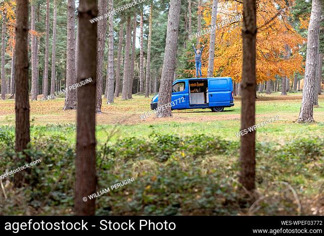 Woman with hand raised standing on top of motor home at Cannock Chase
