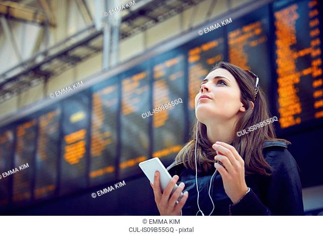 Woman looking at departure information, London, UK