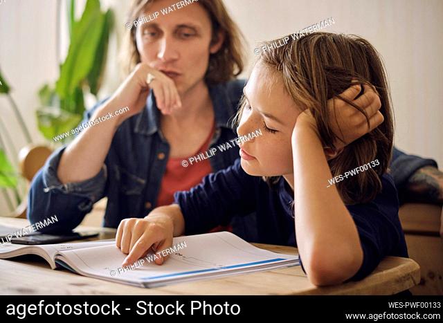 Father assisting son in doing homework at home