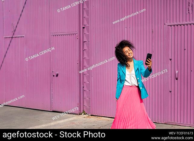 Smiling young woman taking selfie in front of purple metallic cabin