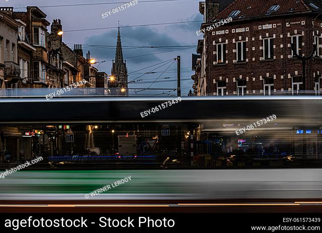 Laeken, Brussels Capital Region - Belgium - 10 28 2020 A bus passing by in motion blur with the cathedral tower in the background at dusk
