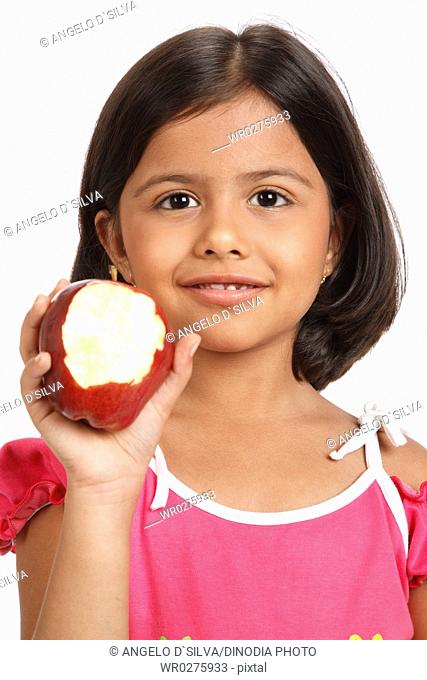 Eight year old girl showing half eaten apple by holding in her right hand near her face MR703U