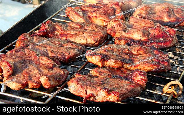 Steak grilling on fire. Process of cooking meat. Steak on barbecue. Preparation of appetizing pork outside. Cooking of pork meat