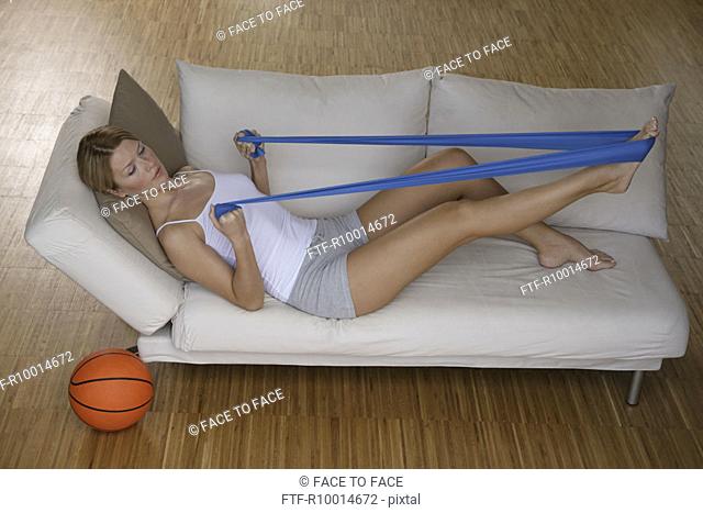 A woman stretching a rubber band by her legs while working out