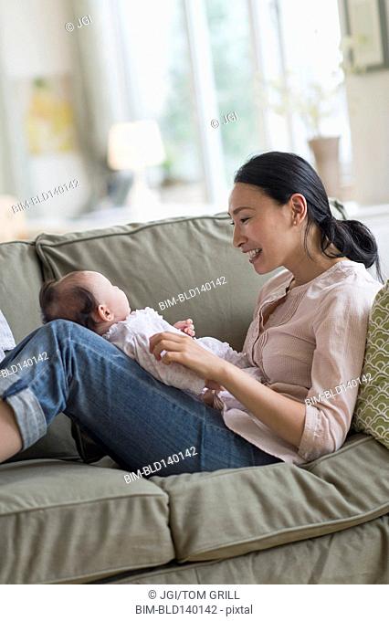 Asian mother playing with baby in living room