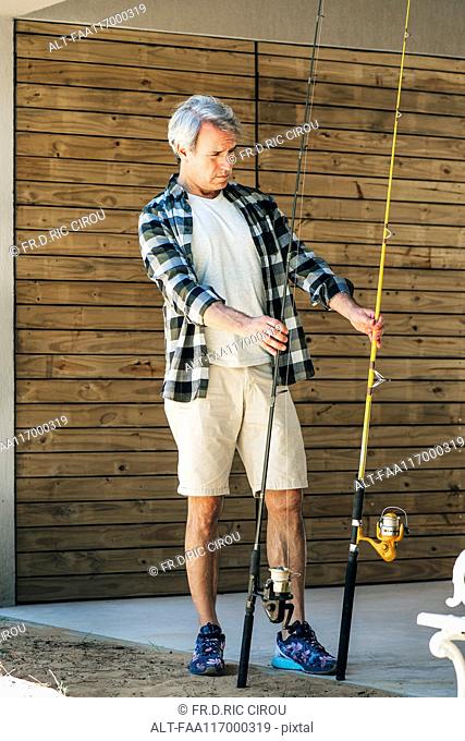 Mature man holding fishing rods