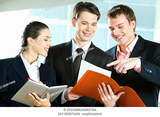 Image of business team in suits discussing papers in mans hand