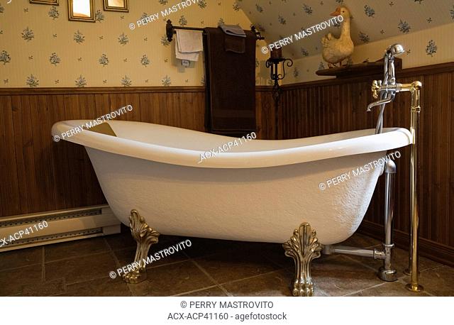 White roll top bathtub in the upstairs bathroom of a 1998 Reproduction of an Old Canadiana cottage style Residential Home, Quebec, Canada