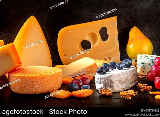 Cheese and fruit. A selection of european cheeses on a dark background