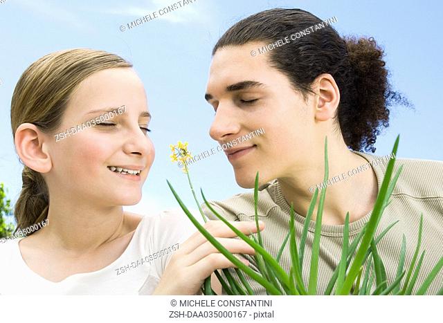 Young man and preteen girl smelling flowering aloe plant, eyes closed