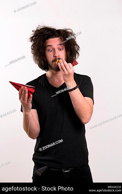 Portrait of a man in party hat blowing in whistle isolated on a white background