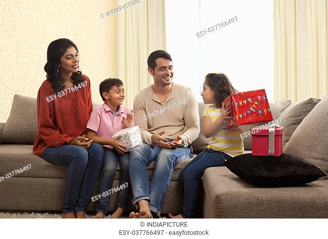 Family with gifts sitting on sofa in living room