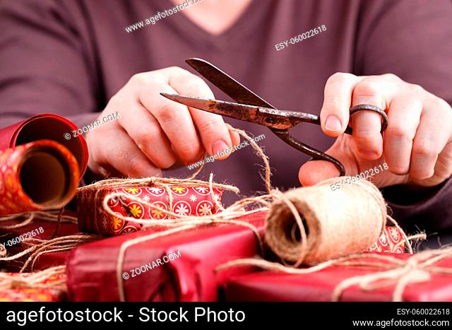 Left handled man cutting a wrapping ribbon on a christmas gift