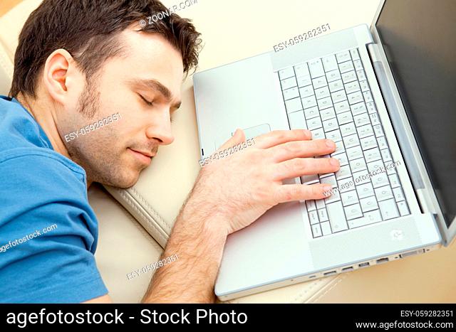 Man overslept by the keyboard of a laptop computer. eyes closed, high-angle view