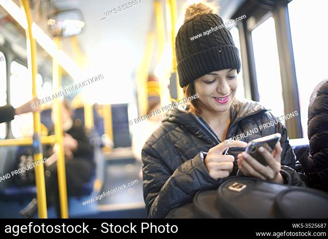 Young woman in bus, using smartphone