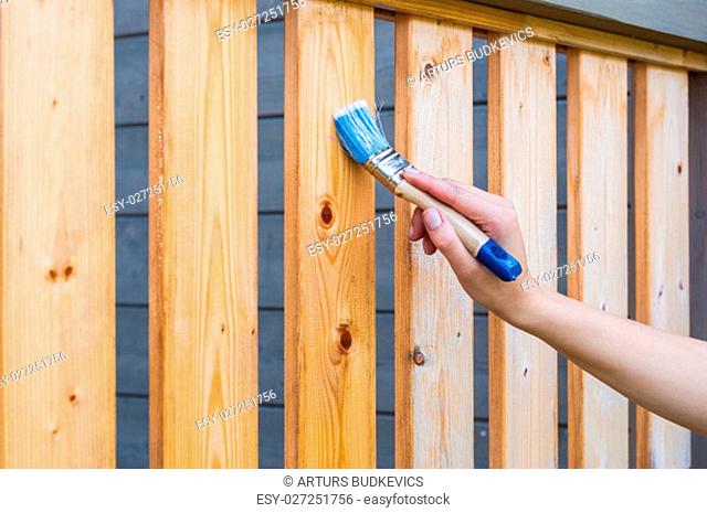 painting terrace railings with a blue paintbrush by hand