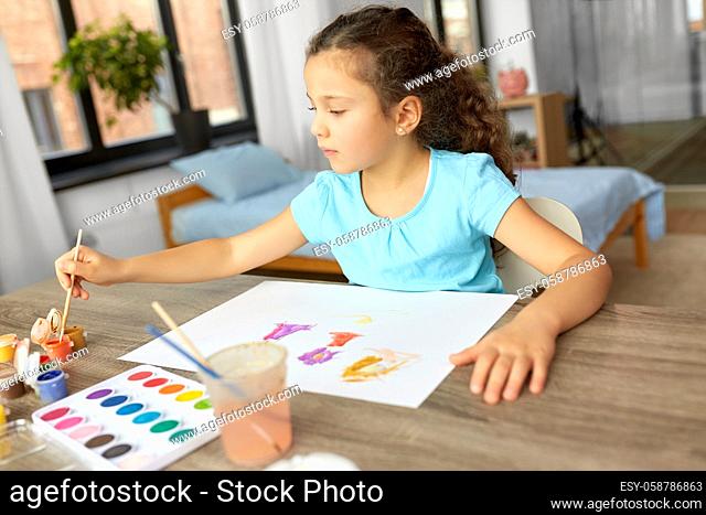 little girl with colors drawing picture at home