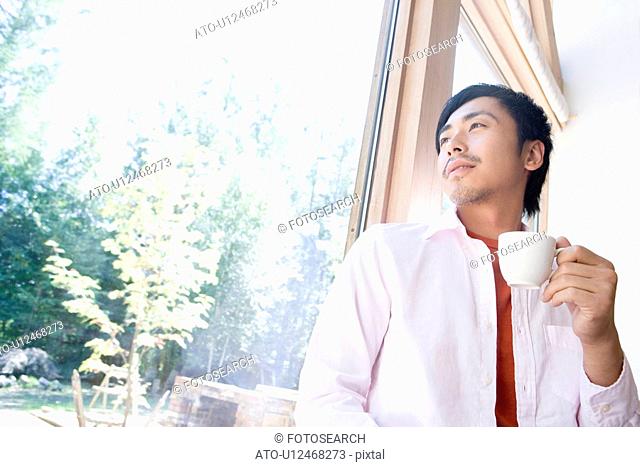 Man Drinking Coffee by Window
