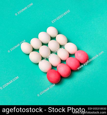 Beautiful Easter composition made of painted pink and white eggs on a green background with copy space. Creative layout for your ideas