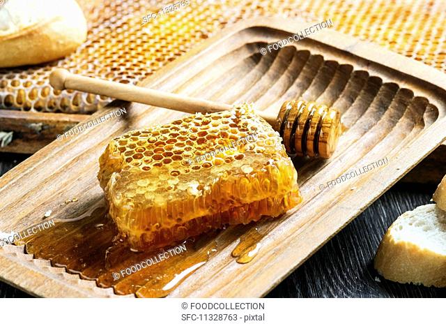 Honeycomb with a honey spoon in an old wooden bowl