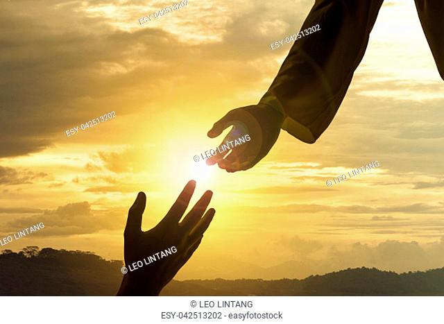 Silhouette of Jesus giving helping hand with sunset background