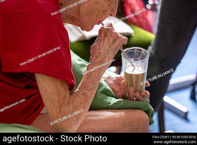 PRODUCTION - 31 July 2023, Berlin: Brigitte Richter, a 97-year-old senior citizen in need of care, drinks coffee from a glass brought to her room by a nurse...