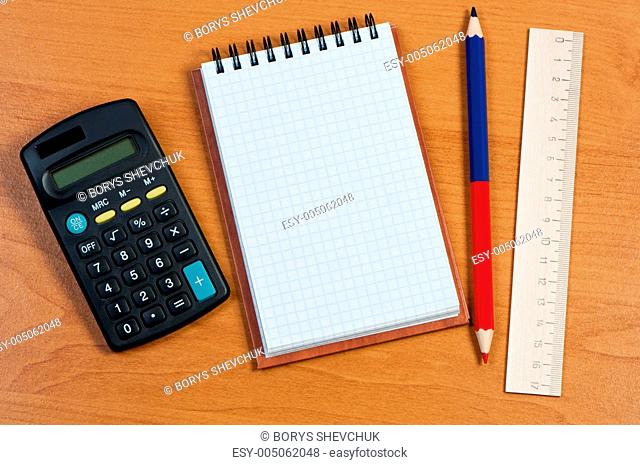 Notepad, calculator, and pencil on the table