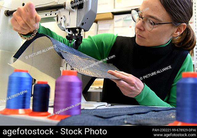 10 February 2023, Saxony, Leipzig: Artist Annekatrin Döll sews a shoulder bag at a sewing machine in her workshop from fish skin from an Irish organic salmon...