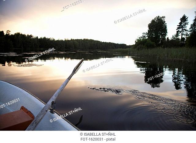 Cropped image of rowboat moored on lake during sunset