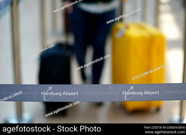 18 May 2022, Hamburg: Airline passengers walk through a terminal at Hamburg Airport with their luggage. The airport is expecting an increased volume of...