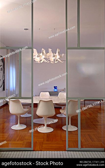 Modern ceiling light suspended over white Eames dining table and chairs