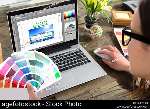 A Woman Holding Color Swatches Using A Laptop With Logo Design Software On The Screen