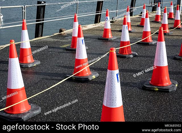Close up of large number of traffic cones lined up on a harbour wall
