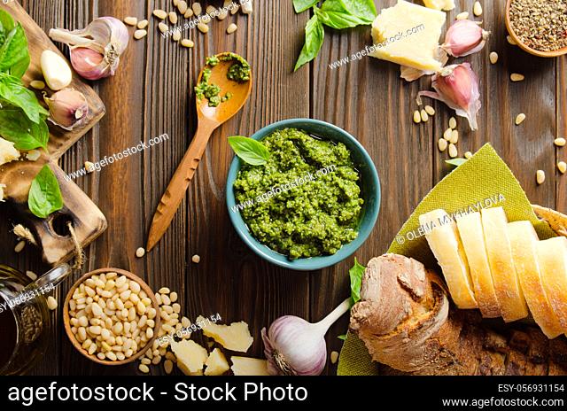 Flat lay view at food background with genovese pesto sauce and its ingredients on wooden kitchen table representing mediterranean cuisine