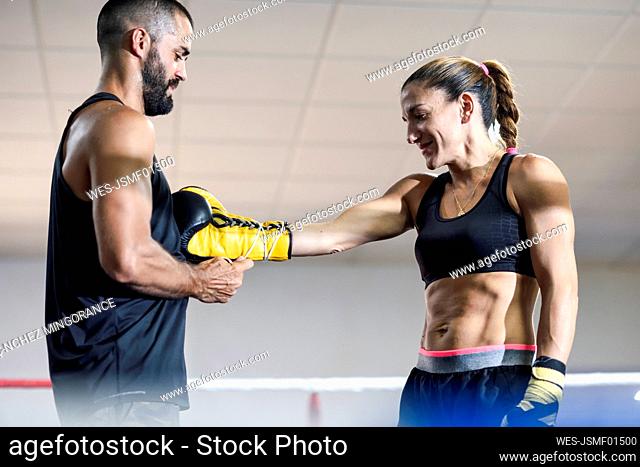 Trainer putting the boxing gloves on a female boxer