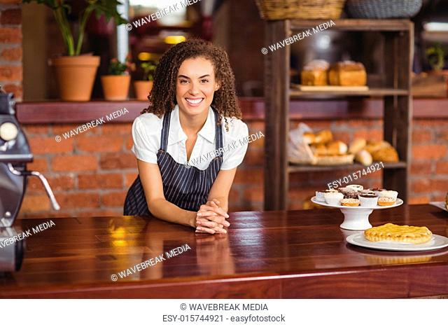 Smiling barista leaning on counter