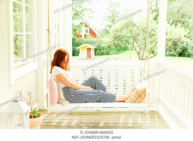 Woman sitting on swing in terrace