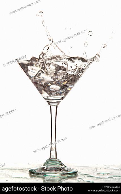 Glass, crystals of ice and pouring water on isolated studio background