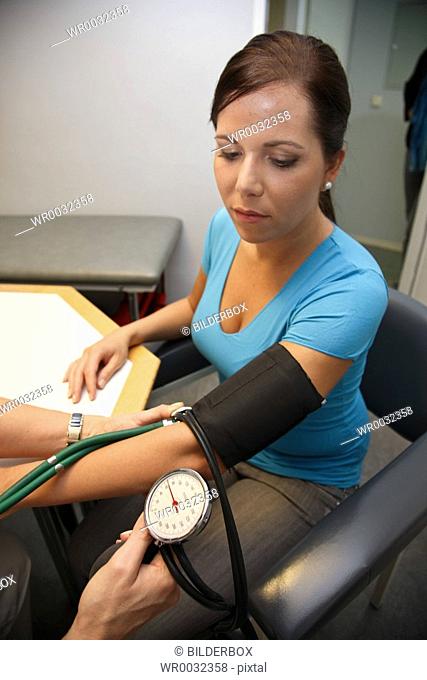 Physician with stethoscope measures blood pressure of a patient