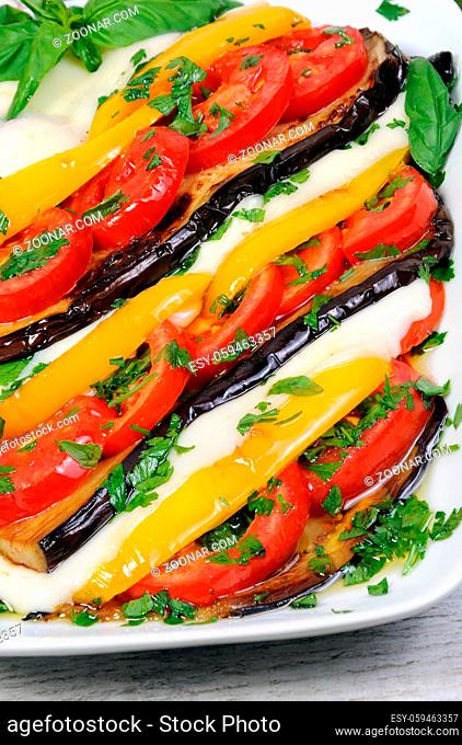 Baked eggplants with tomatoes, yellow pepper and slices mozzarella